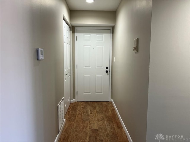 hallway with visible vents, dark wood finished floors, and baseboards