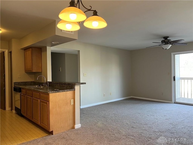 kitchen featuring light carpet, baseboards, dishwashing machine, brown cabinets, and a sink