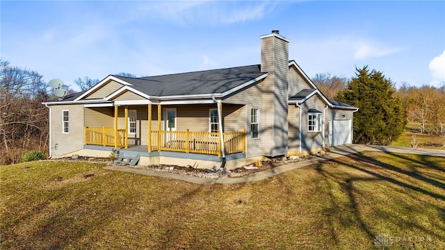 rear view of property featuring a chimney, covered porch, a lawn, and driveway