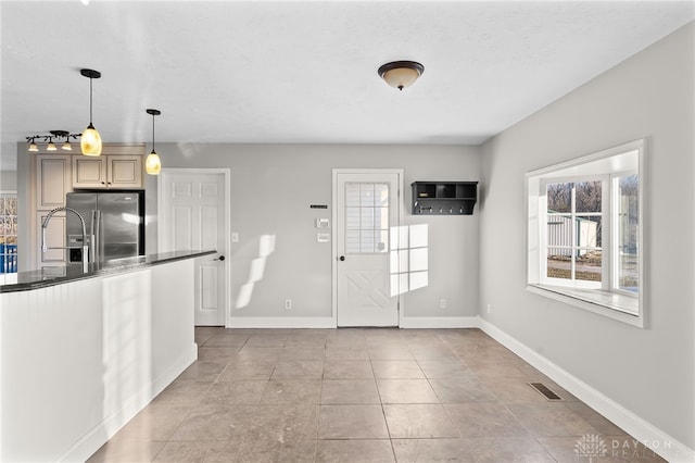 interior space with dark countertops, plenty of natural light, baseboards, and high end fridge