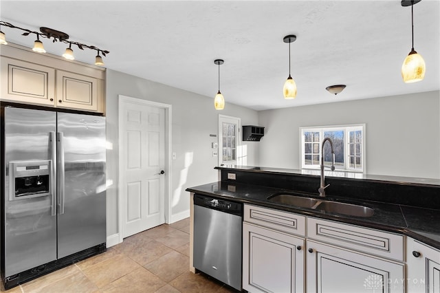 kitchen featuring a sink, baseboards, appliances with stainless steel finishes, dark stone countertops, and pendant lighting