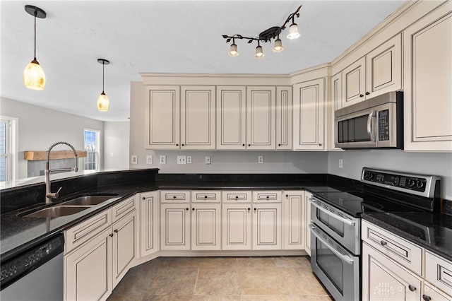 kitchen featuring appliances with stainless steel finishes, cream cabinets, a sink, and decorative light fixtures