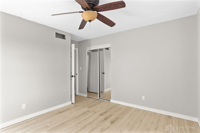 unfurnished bedroom with ceiling fan, wood finished floors, visible vents, baseboards, and a closet