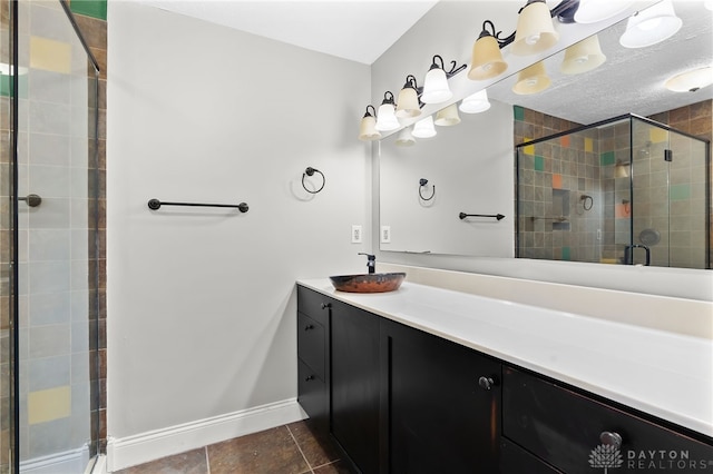 full bath with a stall shower, baseboards, tile patterned floors, a textured ceiling, and vanity