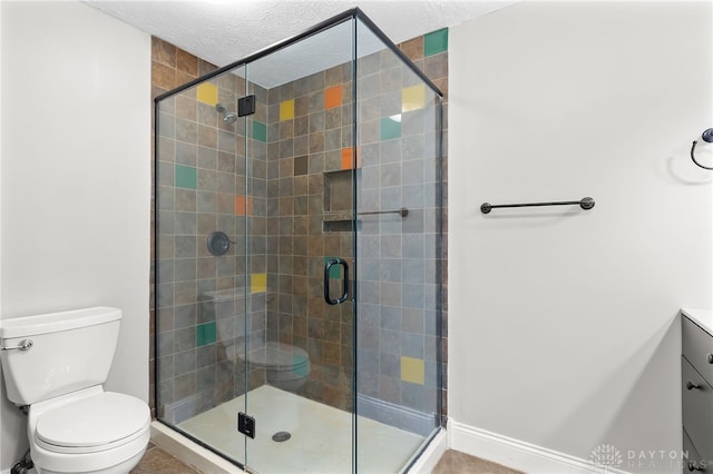 full bathroom featuring a stall shower, a textured ceiling, toilet, and vanity