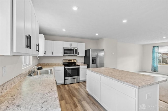 kitchen with stainless steel appliances, light wood-type flooring, light countertops, and a sink