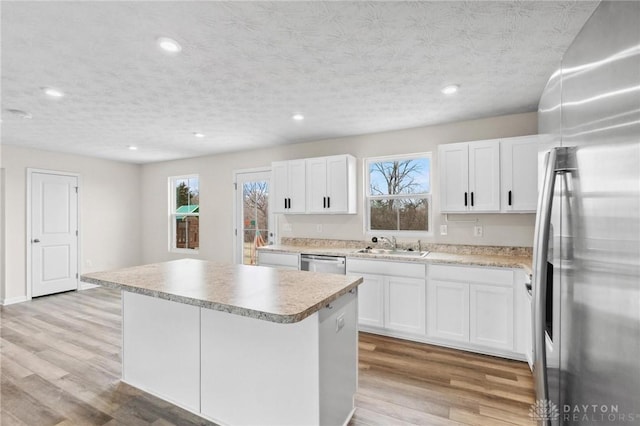 kitchen with appliances with stainless steel finishes, light wood-type flooring, a sink, and a center island