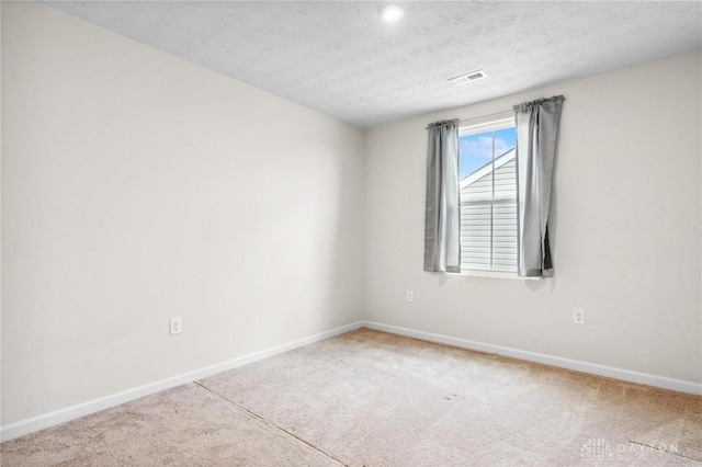 carpeted spare room with a textured ceiling, visible vents, and baseboards