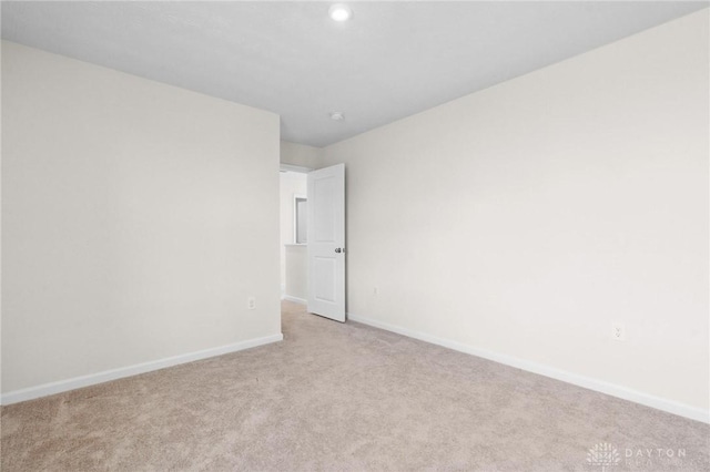 unfurnished room featuring light carpet and baseboards