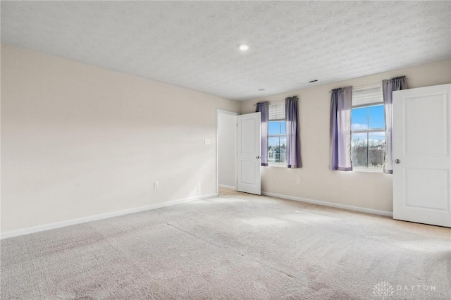 empty room with carpet floors, a textured ceiling, and baseboards