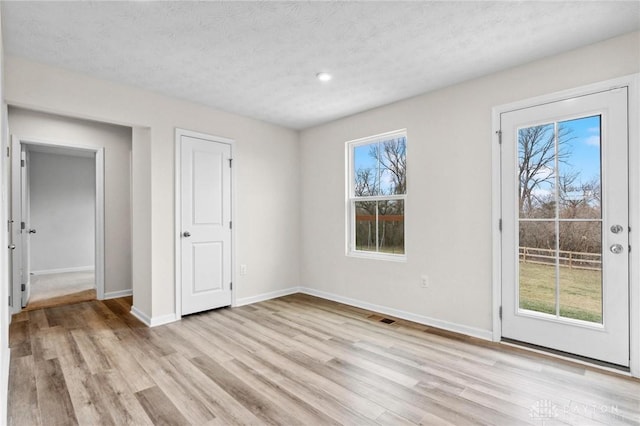 unfurnished bedroom with a textured ceiling, visible vents, baseboards, access to exterior, and light wood-style floors