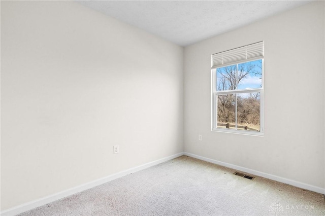 carpeted spare room with visible vents and baseboards