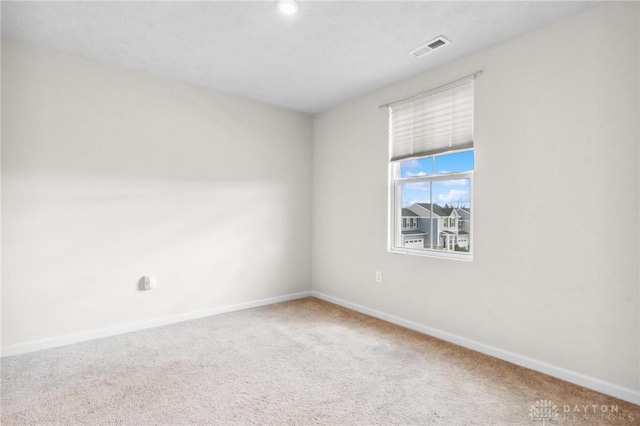 carpeted spare room featuring visible vents and baseboards