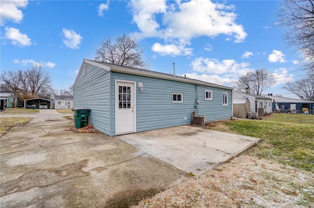 back of house with central air condition unit, a lawn, and a patio