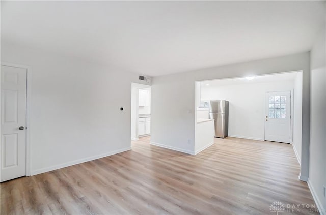 empty room with light wood-style flooring, visible vents, and baseboards