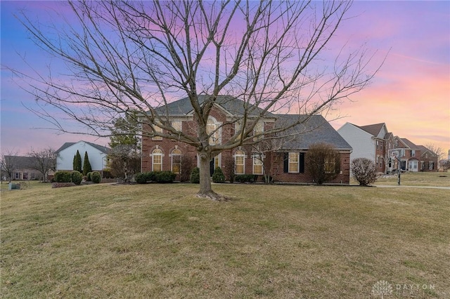 view of front of home featuring brick siding and a yard