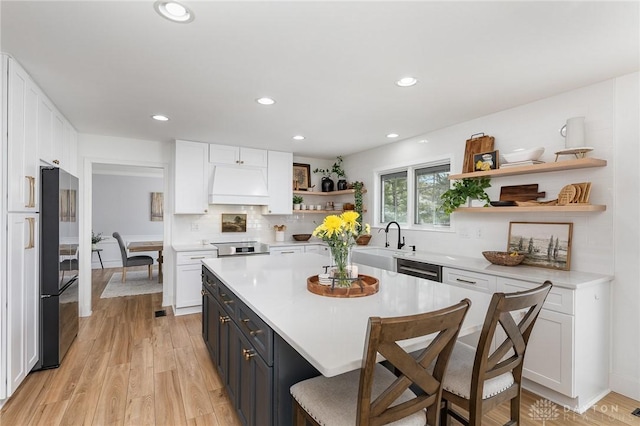 kitchen with light countertops, white cabinets, custom range hood, and open shelves