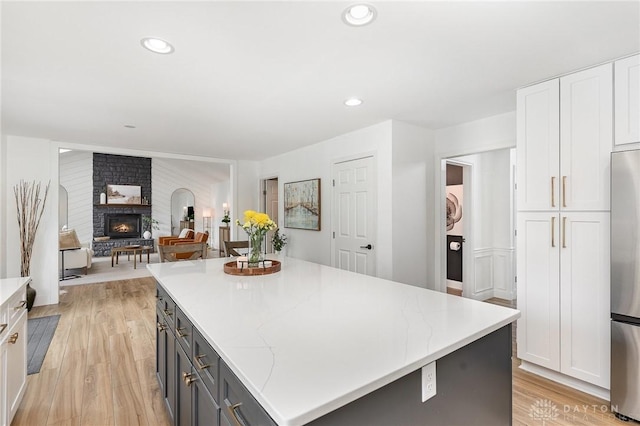 kitchen with stainless steel fridge, a center island, light wood-type flooring, white cabinetry, and recessed lighting