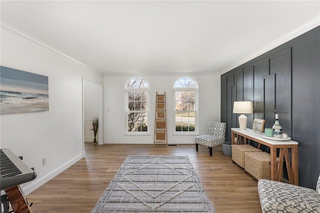 sitting room featuring baseboards, ornamental molding, and wood finished floors