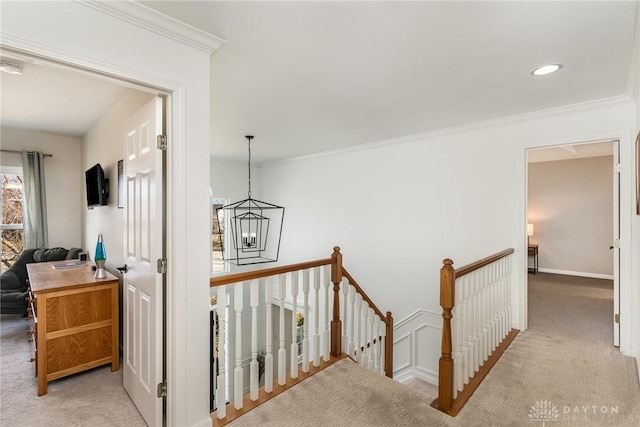 corridor featuring carpet floors, crown molding, and an upstairs landing