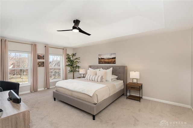 bedroom with baseboards, a tray ceiling, and light colored carpet