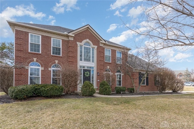 colonial-style house featuring a front lawn and brick siding