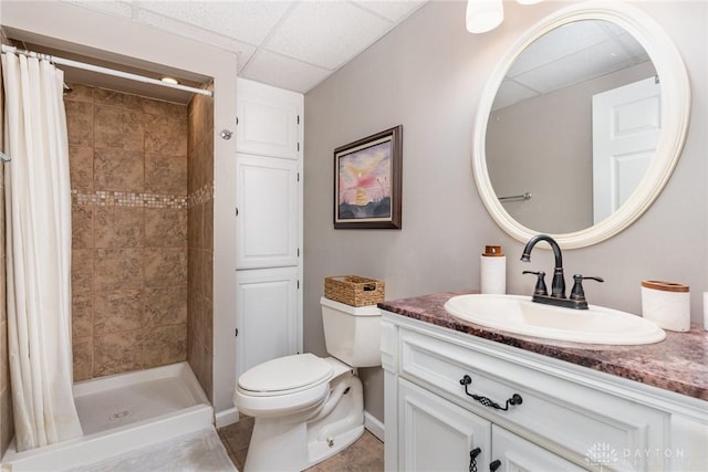 full bathroom featuring toilet, a shower stall, a drop ceiling, and vanity