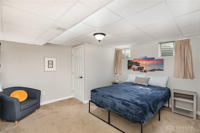 carpeted bedroom featuring a paneled ceiling, visible vents, and baseboards