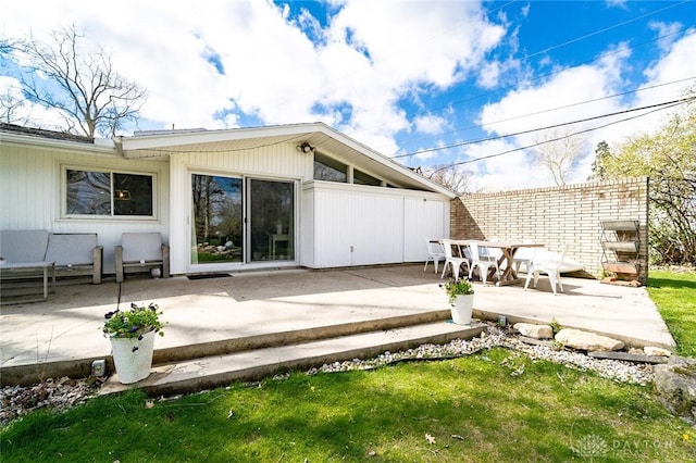 rear view of house featuring a lawn and a patio