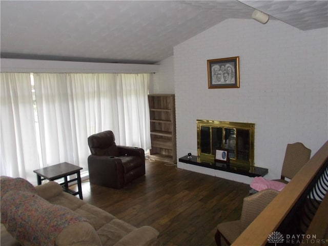 living area featuring a glass covered fireplace, vaulted ceiling, and wood finished floors