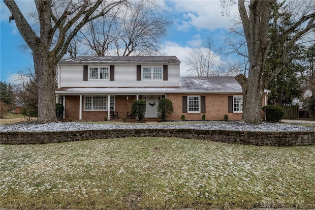 traditional-style home with a front yard and brick siding