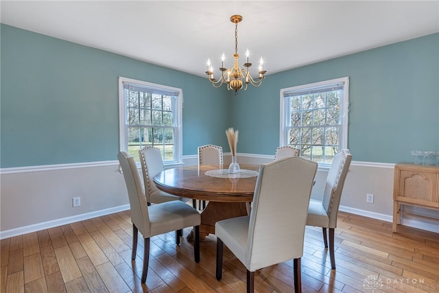 dining room featuring a chandelier, wood finished floors, and baseboards