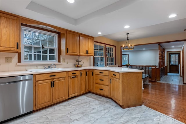 kitchen with a sink, a peninsula, light countertops, and dishwasher