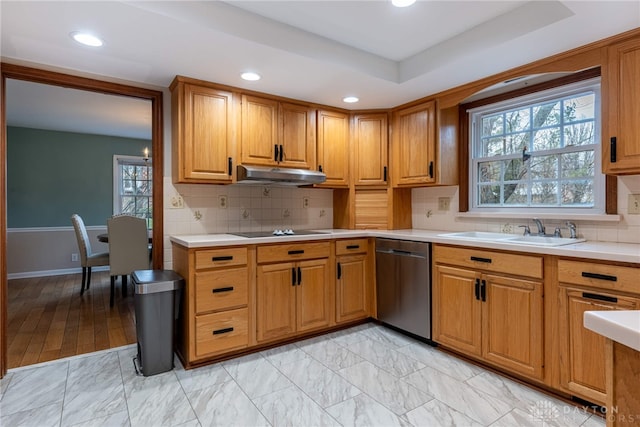 kitchen featuring black electric stovetop, light countertops, stainless steel dishwasher, under cabinet range hood, and a sink