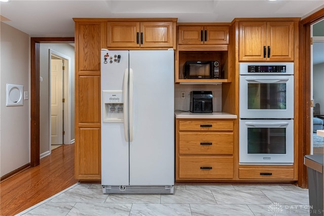 kitchen featuring double wall oven, marble finish floor, white refrigerator with ice dispenser, and brown cabinets