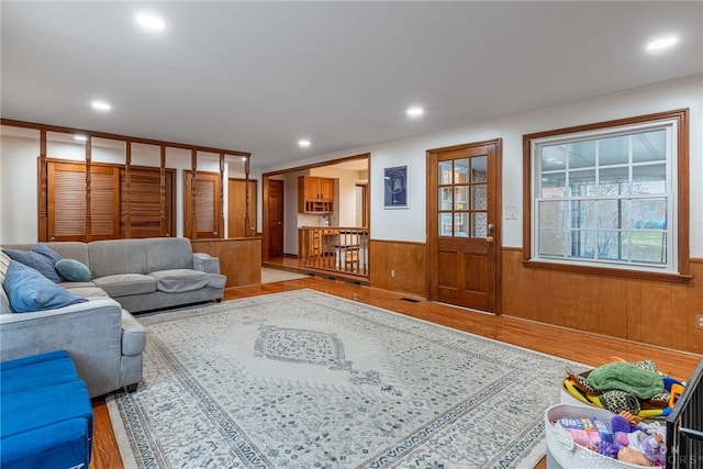 living room featuring light wood-type flooring, a wainscoted wall, visible vents, and recessed lighting