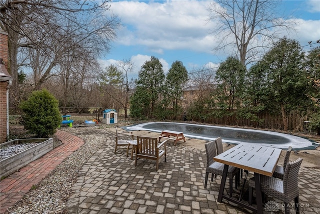 view of patio / terrace with outdoor dining area, fence, a garden, and an outdoor pool