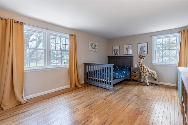 bedroom with light wood-style flooring, multiple windows, and baseboards