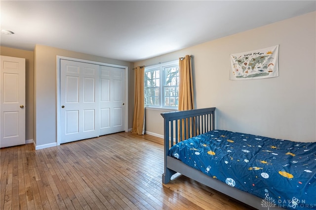 bedroom featuring a closet, wood-type flooring, and baseboards