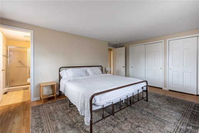 bedroom featuring baseboards, wood-type flooring, connected bathroom, and multiple closets