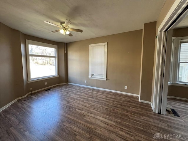 spare room with ceiling fan, a textured ceiling, visible vents, baseboards, and dark wood-style floors