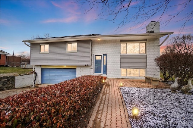 split foyer home with brick siding, a chimney, and an attached garage