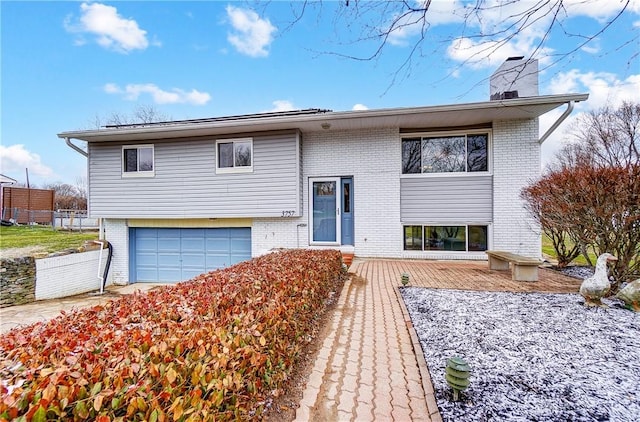 bi-level home with brick siding, a chimney, and an attached garage