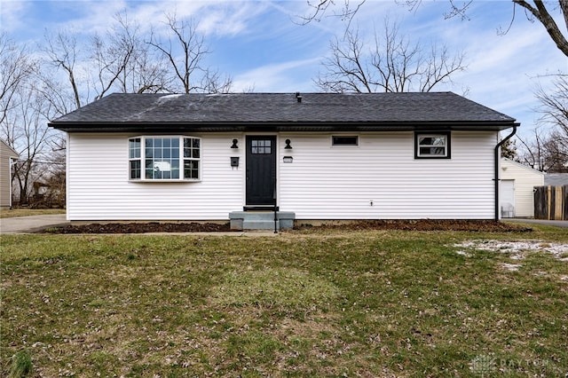 view of front facade featuring entry steps, roof with shingles, and a front yard