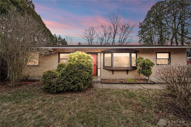 view of front of home with a yard and brick siding