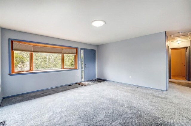 spare room featuring visible vents, carpet, attic access, and baseboards