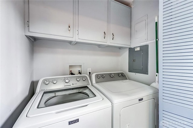 clothes washing area featuring electric panel, cabinet space, and washer and clothes dryer