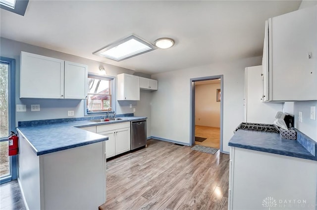 kitchen with stove, a sink, white cabinetry, stainless steel dishwasher, and dark countertops