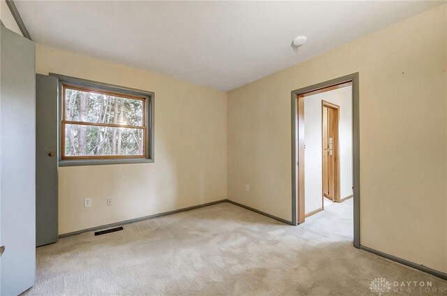 empty room featuring carpet floors, visible vents, and baseboards