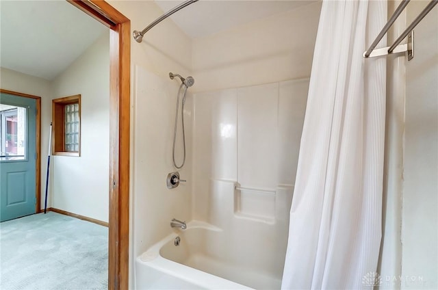 bathroom featuring lofted ceiling, shower / bath combo, and baseboards